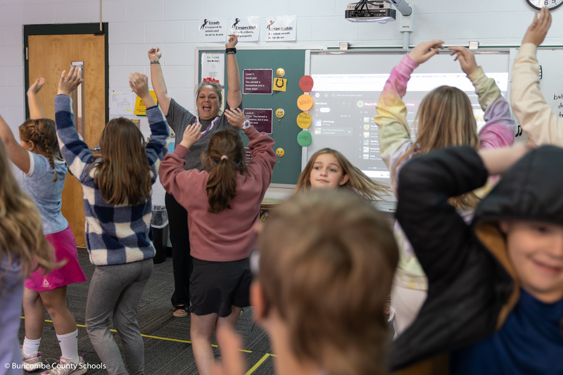 The backs of kids as they spin in a circle doing a hula dance.