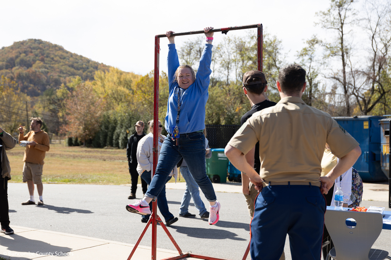 Female teacher dangling from the pull up bar that the Marine Corps set up.