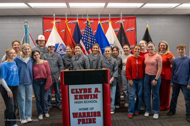 Members of Erwin High School's FCCLA and their advisors pose for a photo in front of military flags