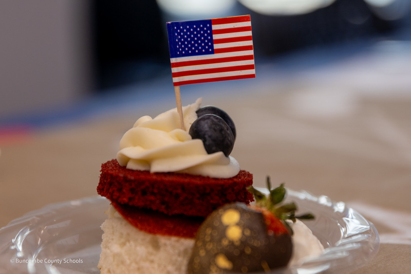 A plated piece of cake with whipped cream and an American flag on the top