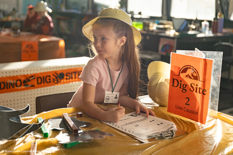 Little girl wearing a hard hat and working at Dig Site 2. One of the many stations students rotated through in the classroom.
