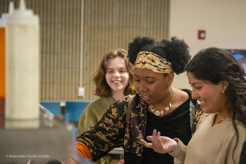Three students smile in the cafeteria  at Buncombe County Early college