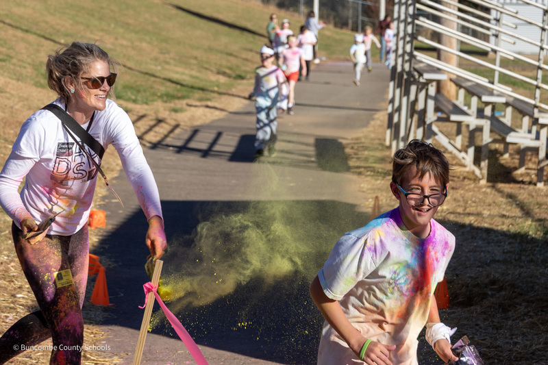 Ms. Cole tosses a puff of yellow powder at a student running around the track