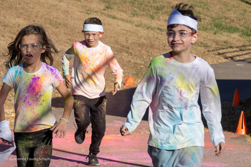 Students run with shirts coated in colorful powder