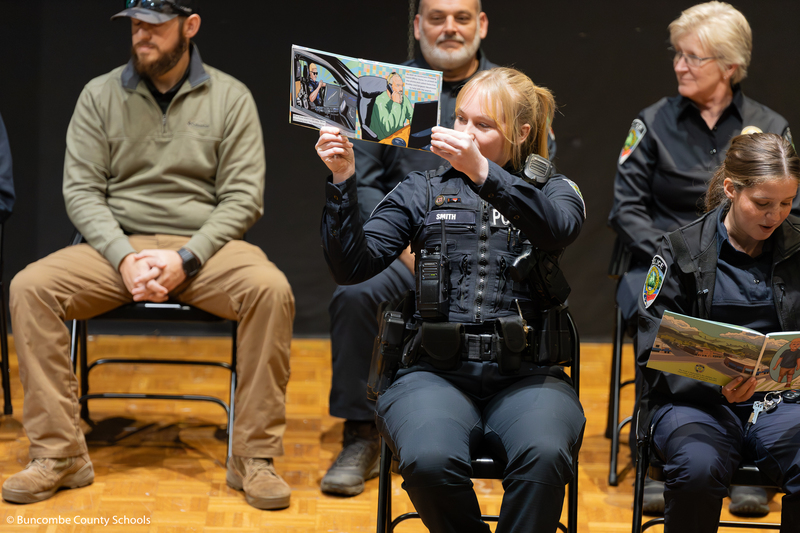 Officer Smith holding the book up to show the students the pictures she drew.