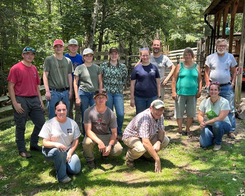 WNCStrong students and advisors pose for a photo outside a barn on a farm.