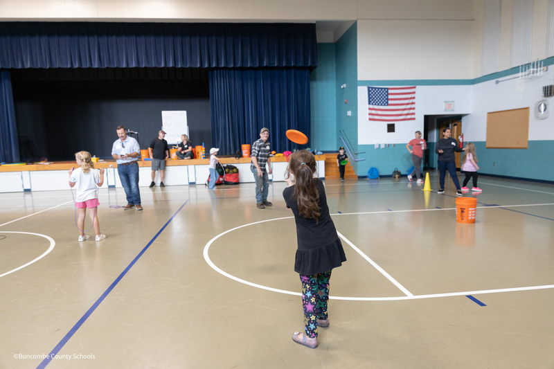 student throwing frisbee at her parent