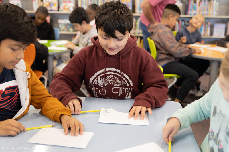 Student smiling as he is looking down at this artwork he created. 
