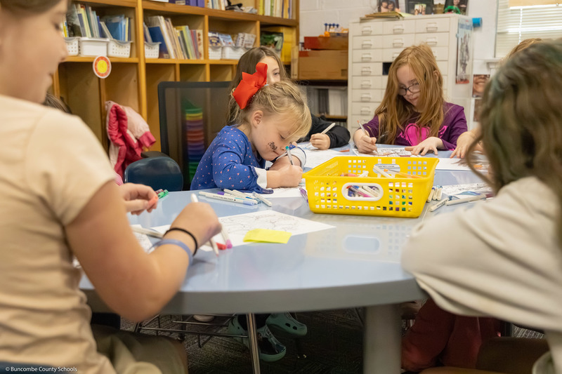 A student smiles while coloring.