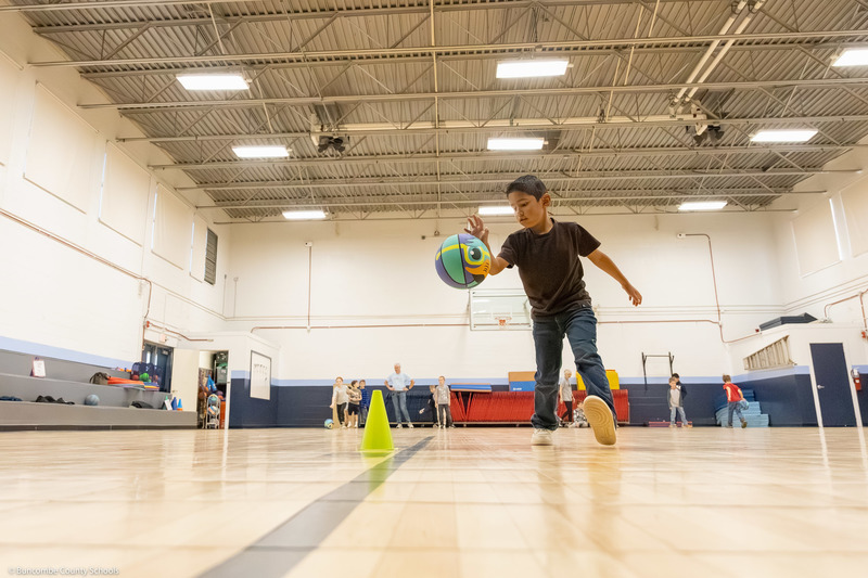 A student dribbles a basketball in the gym.