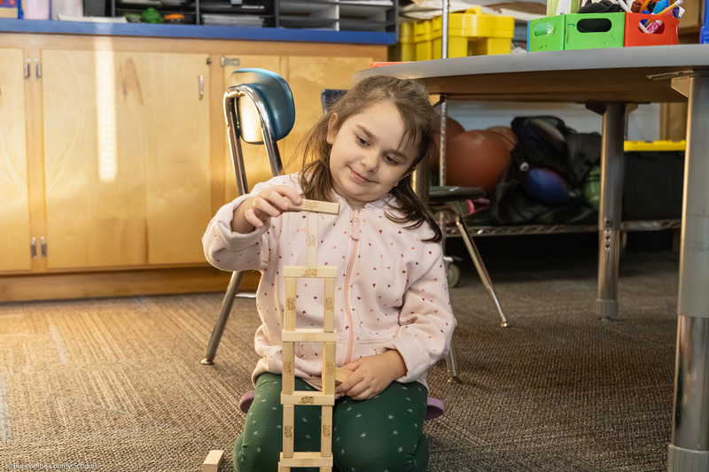 A student places a piece in a Jenga tower.