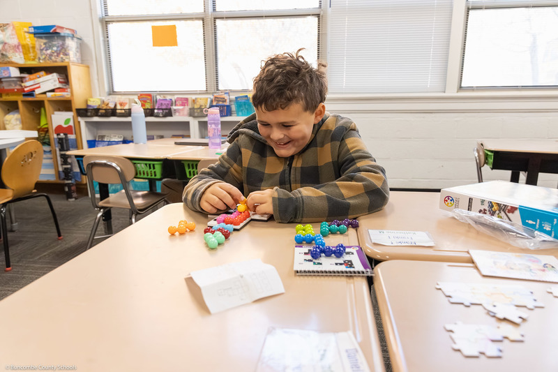 A student works with with colored plastic pieces as part of a thinking game.