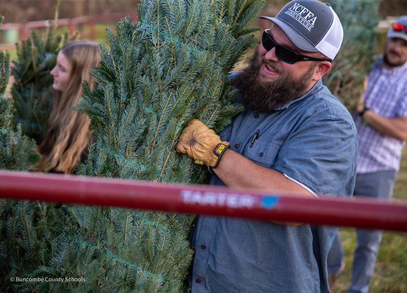 Mr. Frisby smiles as he carries a tree