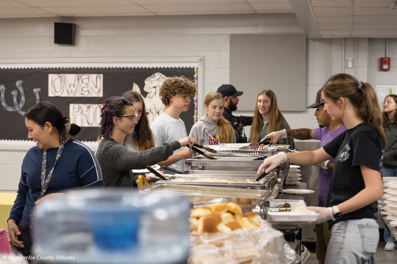 Group of people going through the buffet line to fill their plates. 