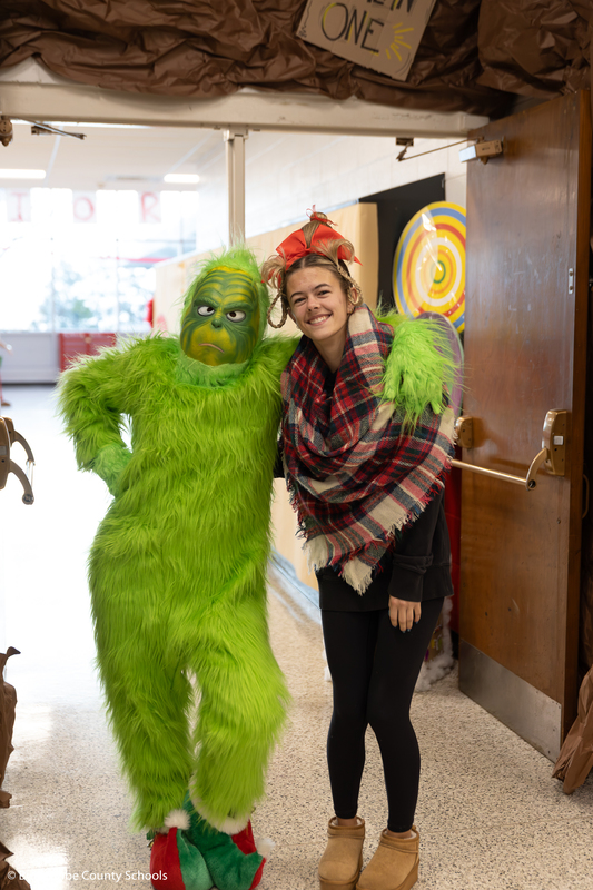 The Grinch and Cindy Lou Who posing together with a photo. 