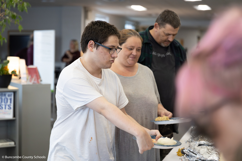 Student with his parents going through the buffet line. 