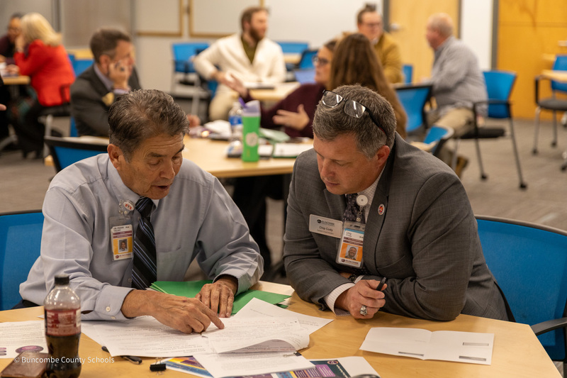 Two people sit at a table and have a small group discussion