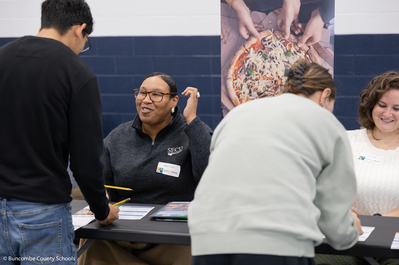 Female banker smiling and giving advice to a high schooler.
