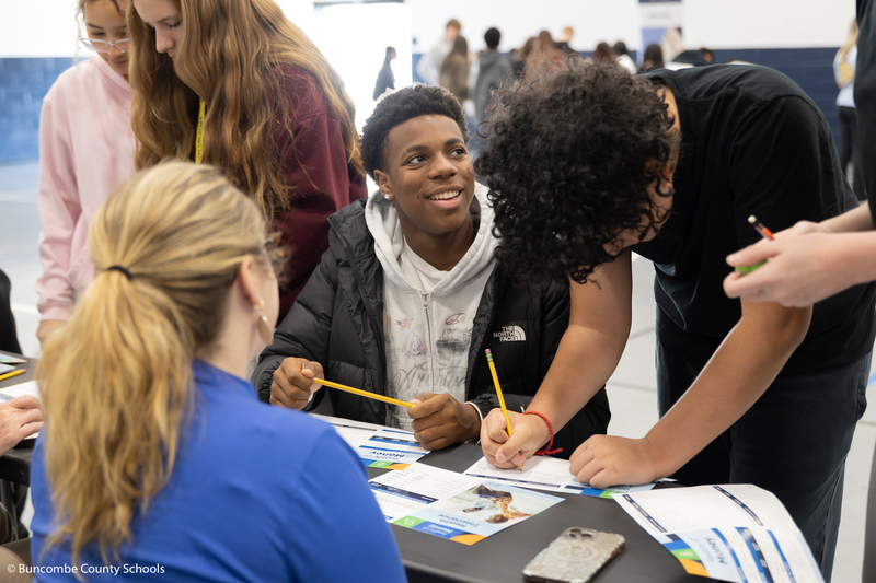 Boy sitting down and looking up at someone talking and smiling.