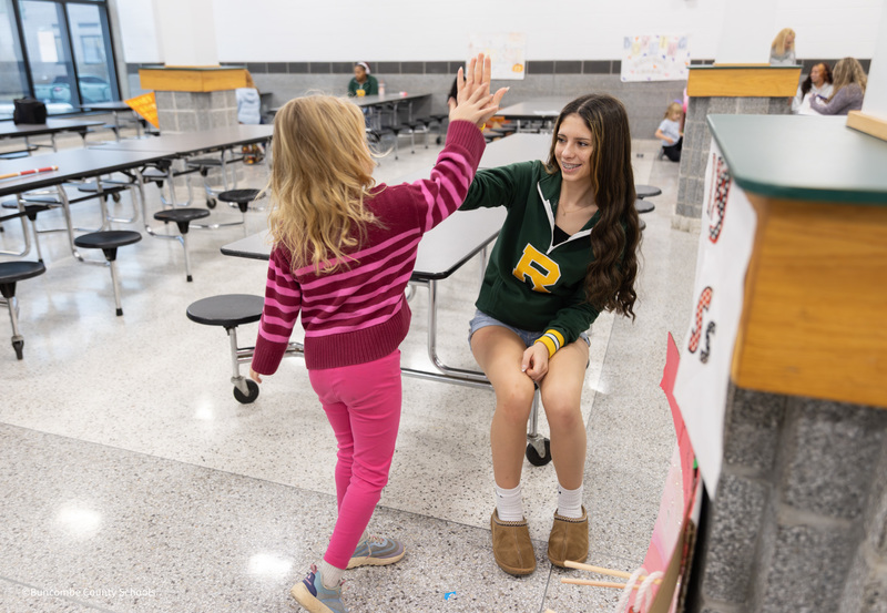 high school student giving high five to young girl