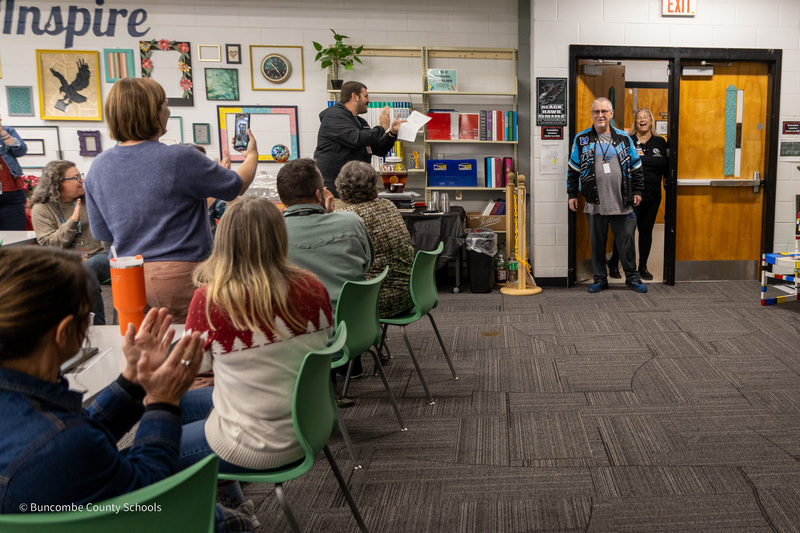 Mr. Roberts walks into the media center smiling to find a group of teachers waiting for him and applauding.