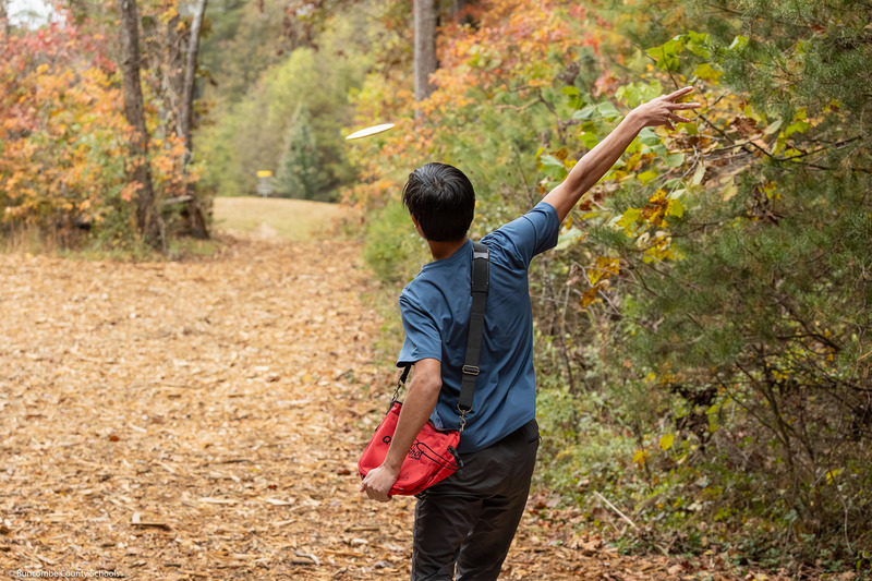 A behind the back shot of a student throwing a disc.