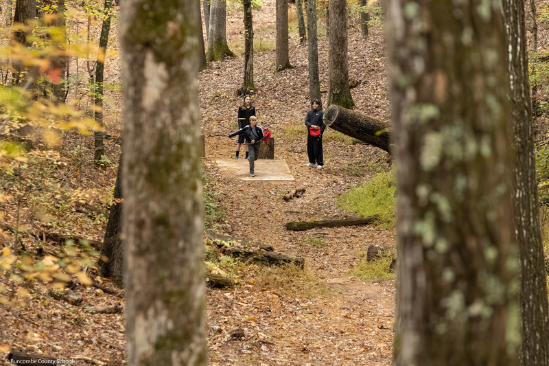 A faraway shot of a student throwing a disc from the tee.