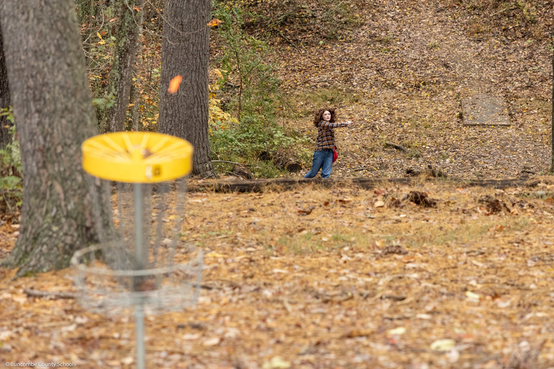 A student tries to putt a disc into the basket.