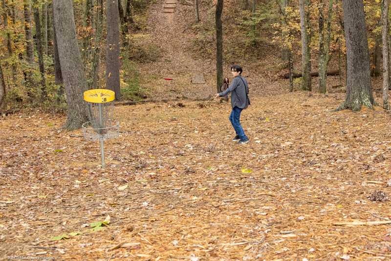 A student tries to putt a disc into the basket.