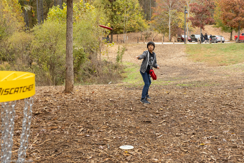 A student tries to putt a disc into the basket.