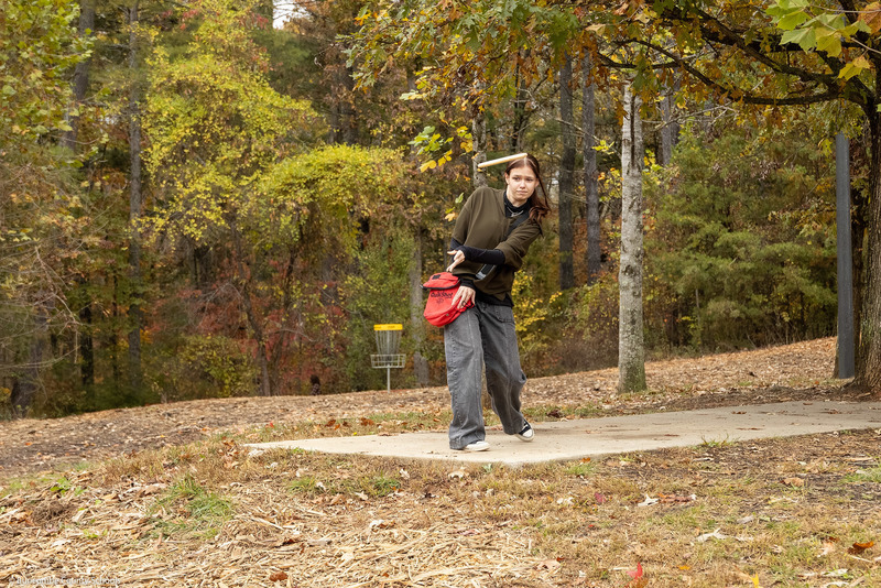 A student launches a disc off the tee platform.