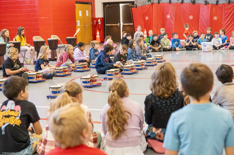 A group of students perform on various drums.