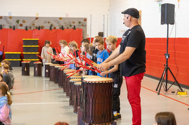 A group of students perform on various drums.