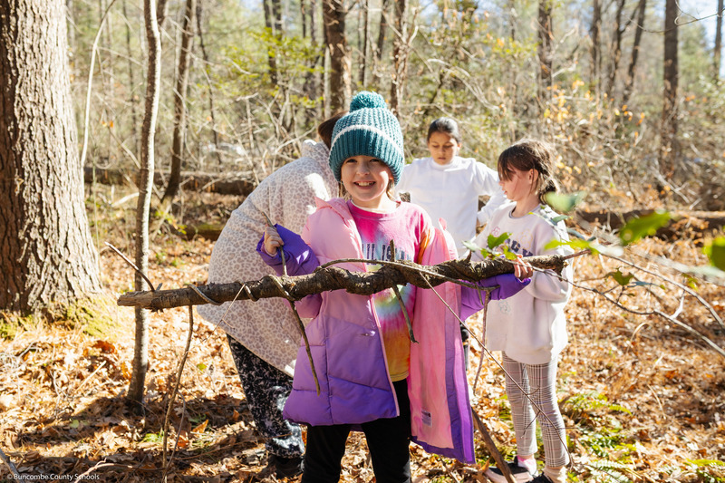 A student smiles while holding a tree branch.