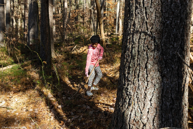 A student gathers a tree branch from the ground.