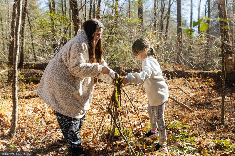 A student and an adult work on a shelter together.