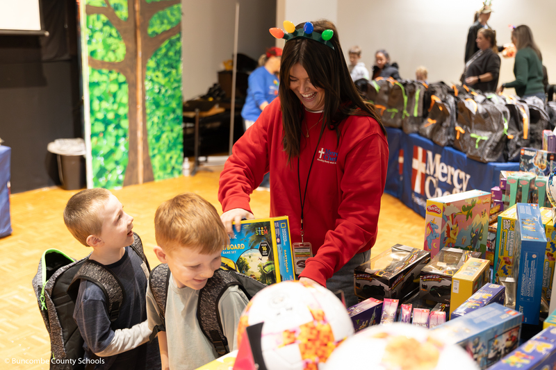Volunteer helping put a toy in a kids backpack.