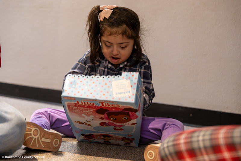 Little girl sitting in the floor admiring her new baby doll.