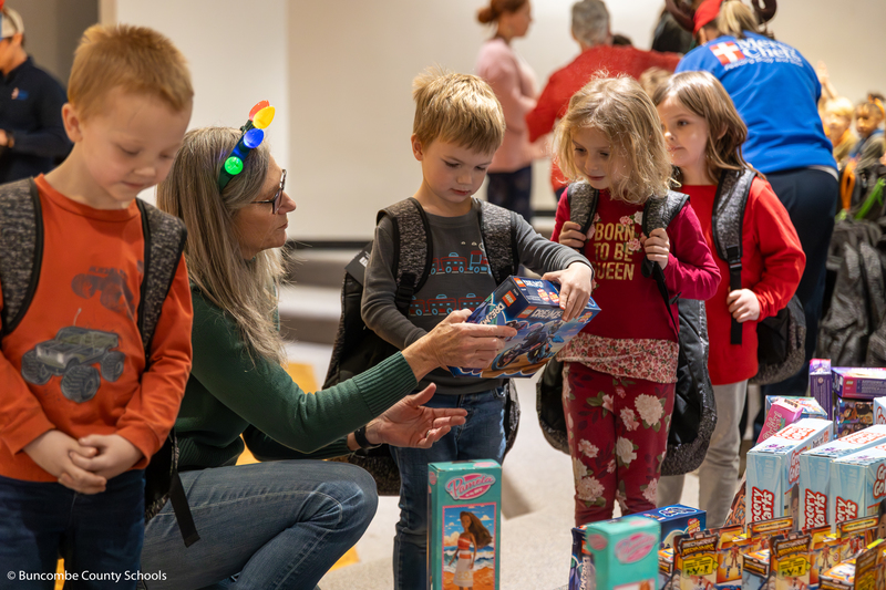 Volunteer helping children pick out a new toy.