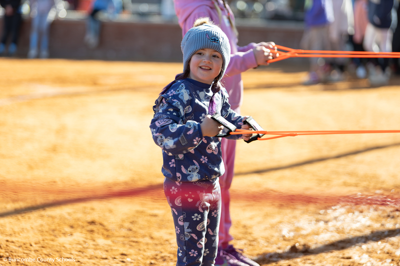 Little girl smiling at the camera and trying to use exercise bands.