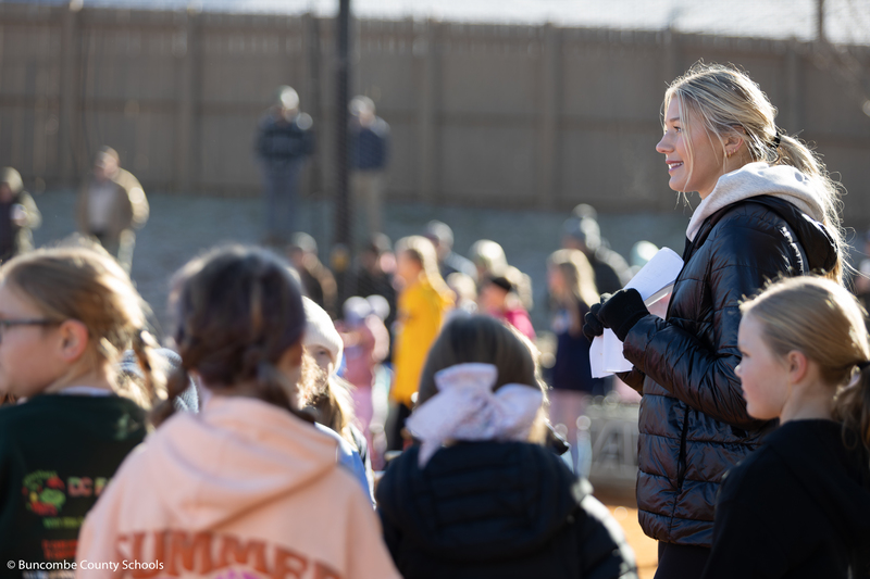Karlyn surrounded by a group of girls. She is smiling as they are talking to her.