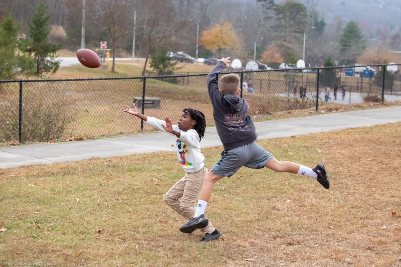 Two students try to catch a football.