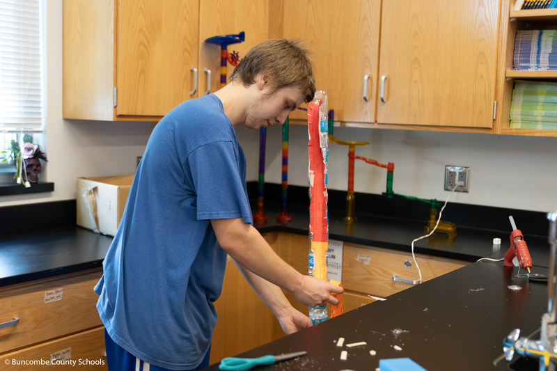 Student gluing empty water bottles together. 
