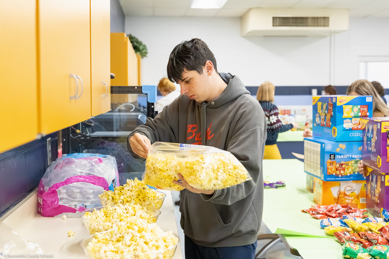 An Enka High student pours popcorn into a bowl.