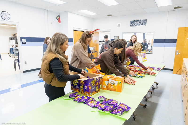 Enka High SGA members lay snacks out on a table.