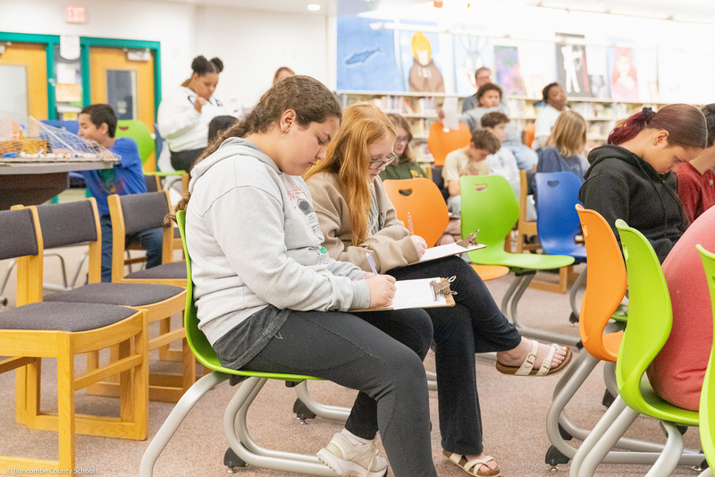 A student takes notes during a presentation.