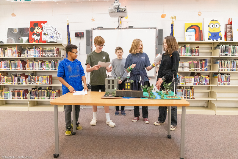 Students give a presentation while standing behind their Future City diorama.
