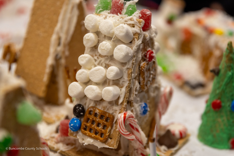 A close up of a gingerbread house with mini marshmallows on the roof.