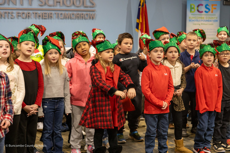 students dressed in red and green elf hats singing
