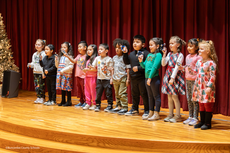 students singing jingle bells while holding bells